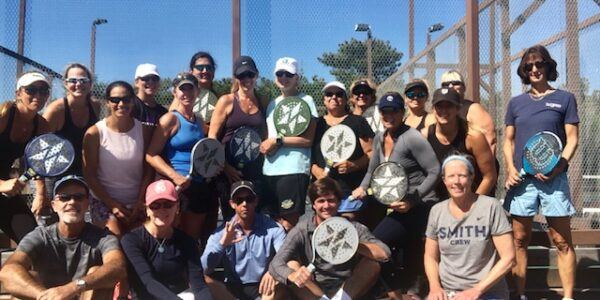 Large session group holding paddles on court