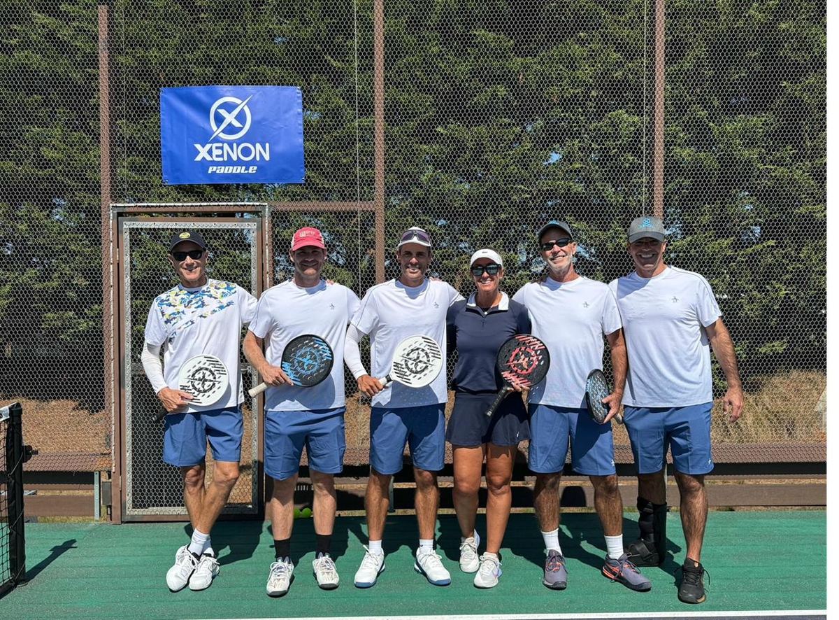 Coaching team with paddles in front of Xenon Paddle banner